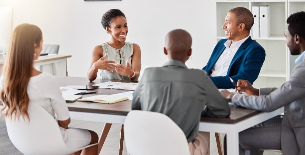 A diverse group of business professionals in a collaborative meeting around a conference table in a bright, modern office
